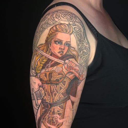 A colorful illustrative tattoo of a warrior woman with a sword and Celtic patterns on the upper arm — by Sandra Price, los angeles