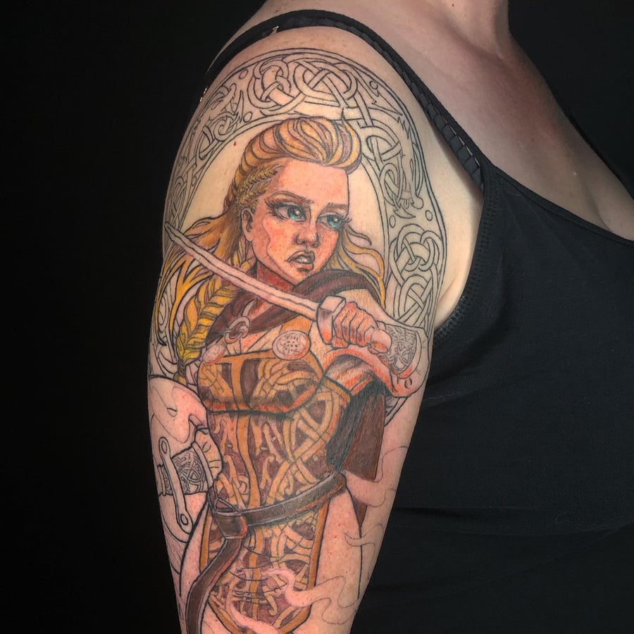 A colorful illustrative tattoo of a warrior woman with a sword and Celtic patterns on the upper arm — by Sandra Price, los angeles