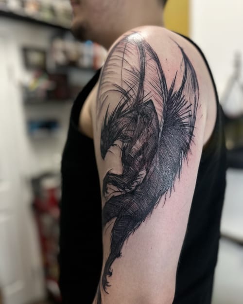 A bold black and grey sketch style dragon tattoo on the upper arm — by Maddie Ramirez, los angeles