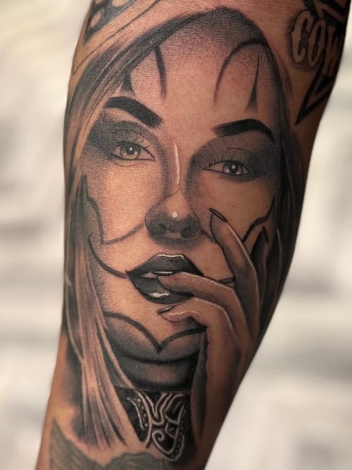A realistic black and grey portrait of a woman on the forearm, featuring detailed shading and expressive facial features — by Josue Bravo, los angeles