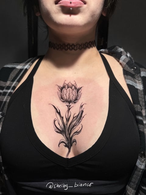 black and grey flower bud with sweeping curled leaves in fine shading on the sternum — by shelby bianco, los angeles