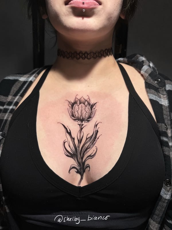 black and grey flower bud with sweeping curled leaves in fine shading on the sternum — by shelby bianco, los angeles