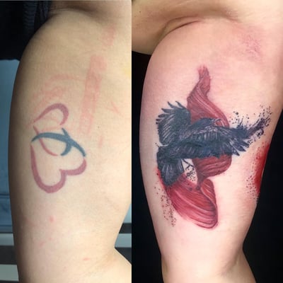 A bold tattoo of a bird in flight with abstract red elements on the upper arm, combining realism and abstract styles — by Sandra Price, los angeles