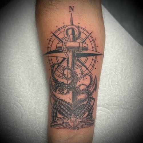 A bold black and grey tattoo of an anchor entwined with an octopus and compass on the forearm, featuring detailed linework and shading — by Sandra Price, los angeles