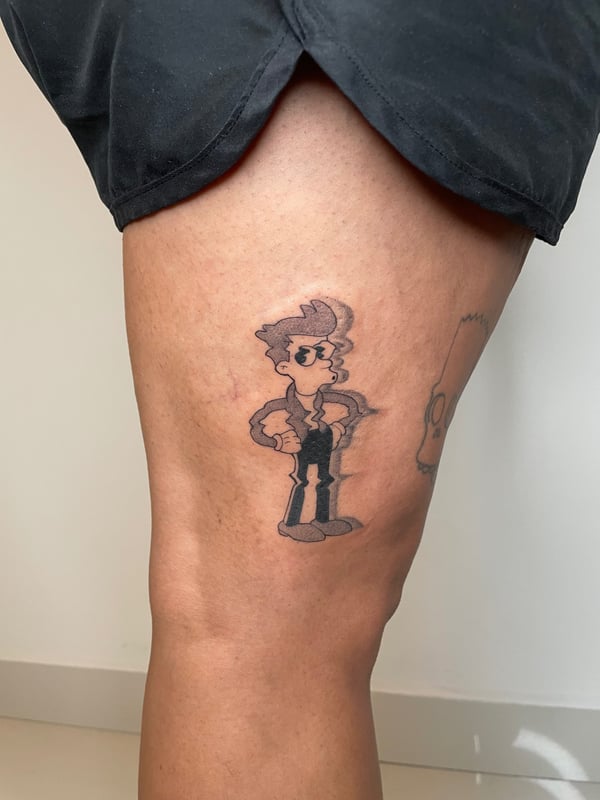 A whimsical black and grey cartoon character tattoo on the thigh, featuring bold outlines and simple shading — by Brian Kies, los angeles