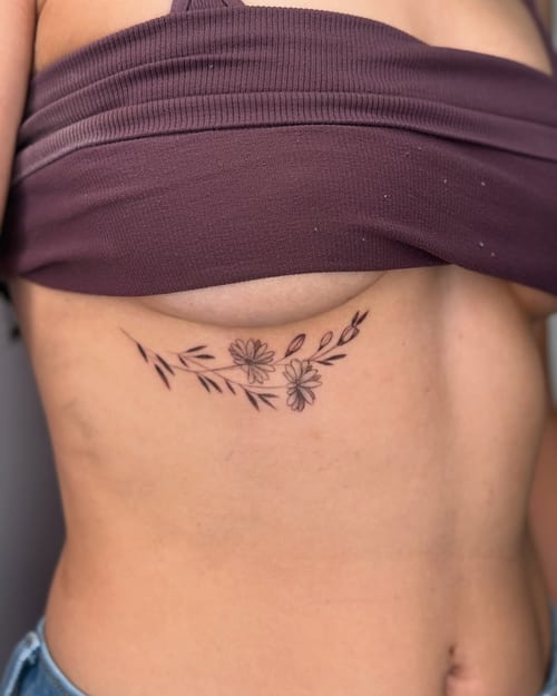 A delicate fine line floral tattoo on the rib, featuring minimalistic black and grey flowers and leaves — by zealous, los angeles