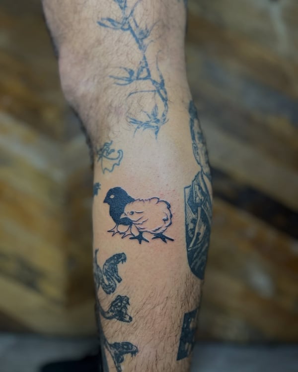 A minimalist blackwork tattoo of a chick on the leg, featuring simple lines and shading — by Dylan Aiello, los angeles