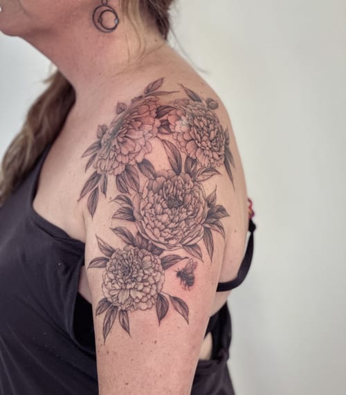 A delicate black and grey tattoo of peony flowers and a bee on the shoulder, featuring intricate floral details — by Melanie Benoit, los angeles