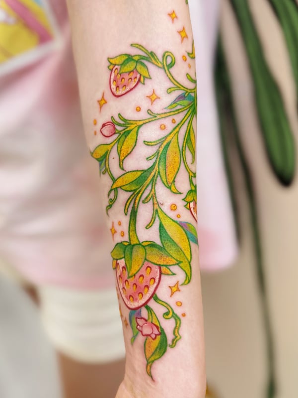 A colorful neo-traditional tattoo on the forearm featuring strawberries and floral elements with vibrant green leaves and pink flowers — by Tweetwee, west covina, ca