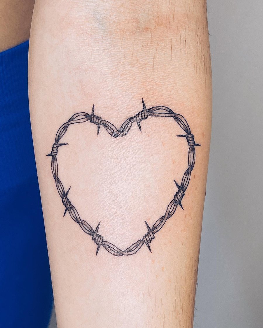A minimalist black and grey barbed wire heart tattoo on the arm, featuring clean linework — by Level tattoo, los angeles