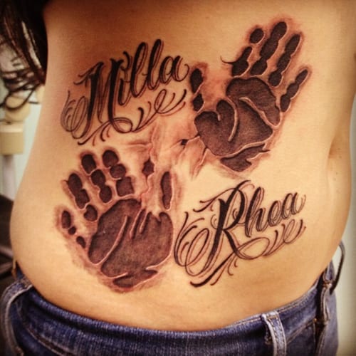 A bold black and grey tattoo featuring handprints and script names on the rib area — by Johnny Ayala, los angeles