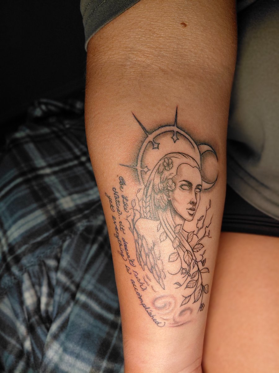 A fine line tattoo on the forearm depicting a woman with floral elements and a crescent moon, rendered in black and grey — by anoetic.designs.ultd, los angeles
