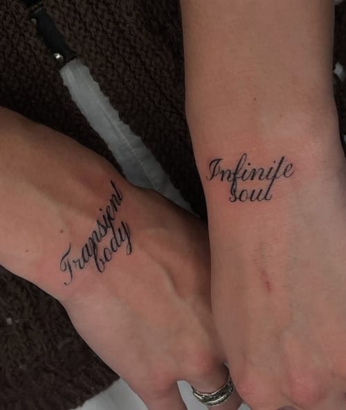 Simple black script tattoos on the wrists with the phrases 'Transient body' and 'Infinite soul' — by Level tattoo, los angeles