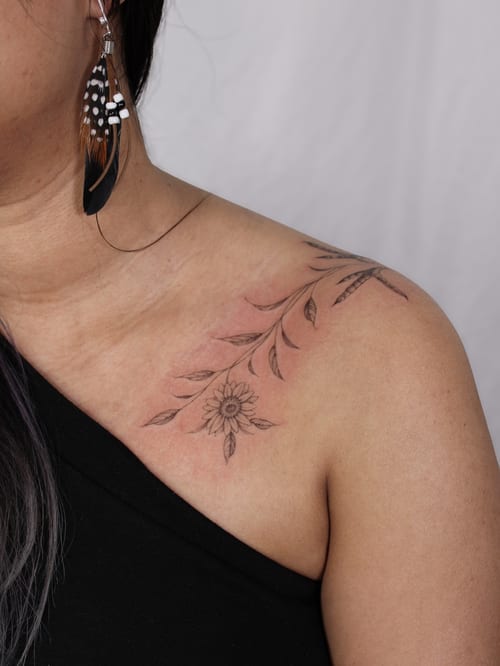 A delicate black and grey floral branch tattoo on the shoulder, featuring fine line work and intricate details — by Melanie Benoit, los angeles