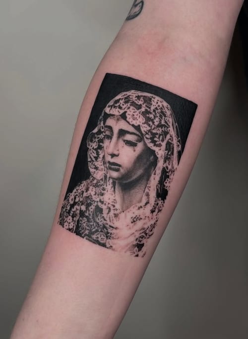 A black and grey realism portrait of the Virgin Mary on the forearm, featuring intricate details and soft shading — by Level tattoo, los angeles