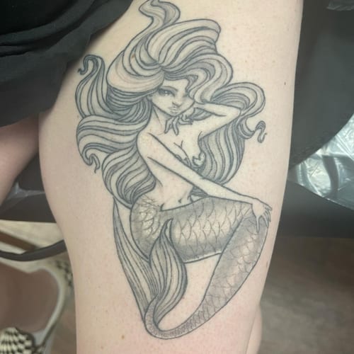 A black and grey illustrative mermaid tattoo on the thigh, featuring flowing hair and delicate shading — by Sandra Price, los angeles