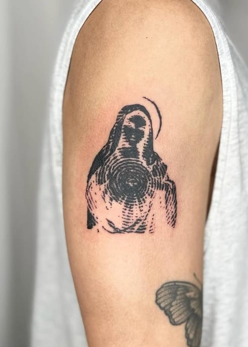 A blackwork tattoo on the upper arm depicting a religious figure in an abstract, ignorant style with bold lines and minimal detail — by Level tattoo, los angeles