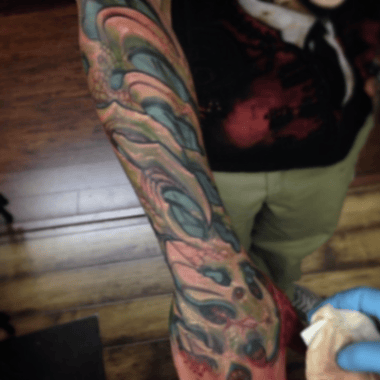 A colorful abstract full sleeve tattoo with swirling patterns and vibrant hues, showcasing a new school style — by tyler_whitlock, los angeles