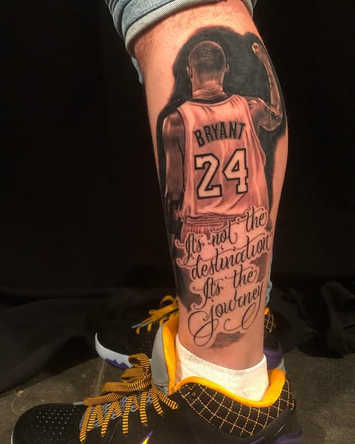 A realistic black and grey tattoo of a basketball player with a quote on the calf, featuring detailed shading and bold script — by Johnny Ayala, los angeles