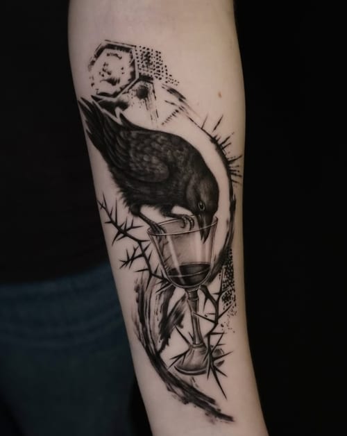 A black and grey illustrative tattoo of a bird perched on a wine glass on the forearm, featuring dotwork and abstract elements — by Jian Liang, los angeles