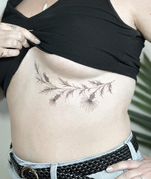 A delicate black and grey fine line botanical branch tattoo on the rib, featuring intricate floral details — by Melanie Benoit, los angeles