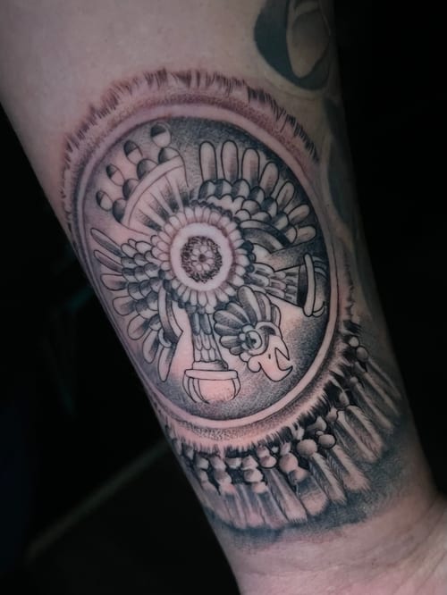 A black and grey dotwork tattoo on the forearm featuring a circular sacred geometry design with a crown and intricate patterns — by Josue Bravo, los angeles