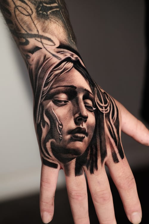 A black and grey realism portrait of a woman's face on the hand, featuring detailed shading and soft contours — by Johnny Ayala, los angeles