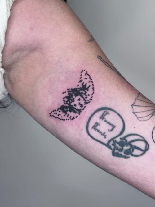 A minimalist pixelated butterfly tattoo in black ink on the inner arm, featuring an ignorant style design — by Brian Kies, los angeles