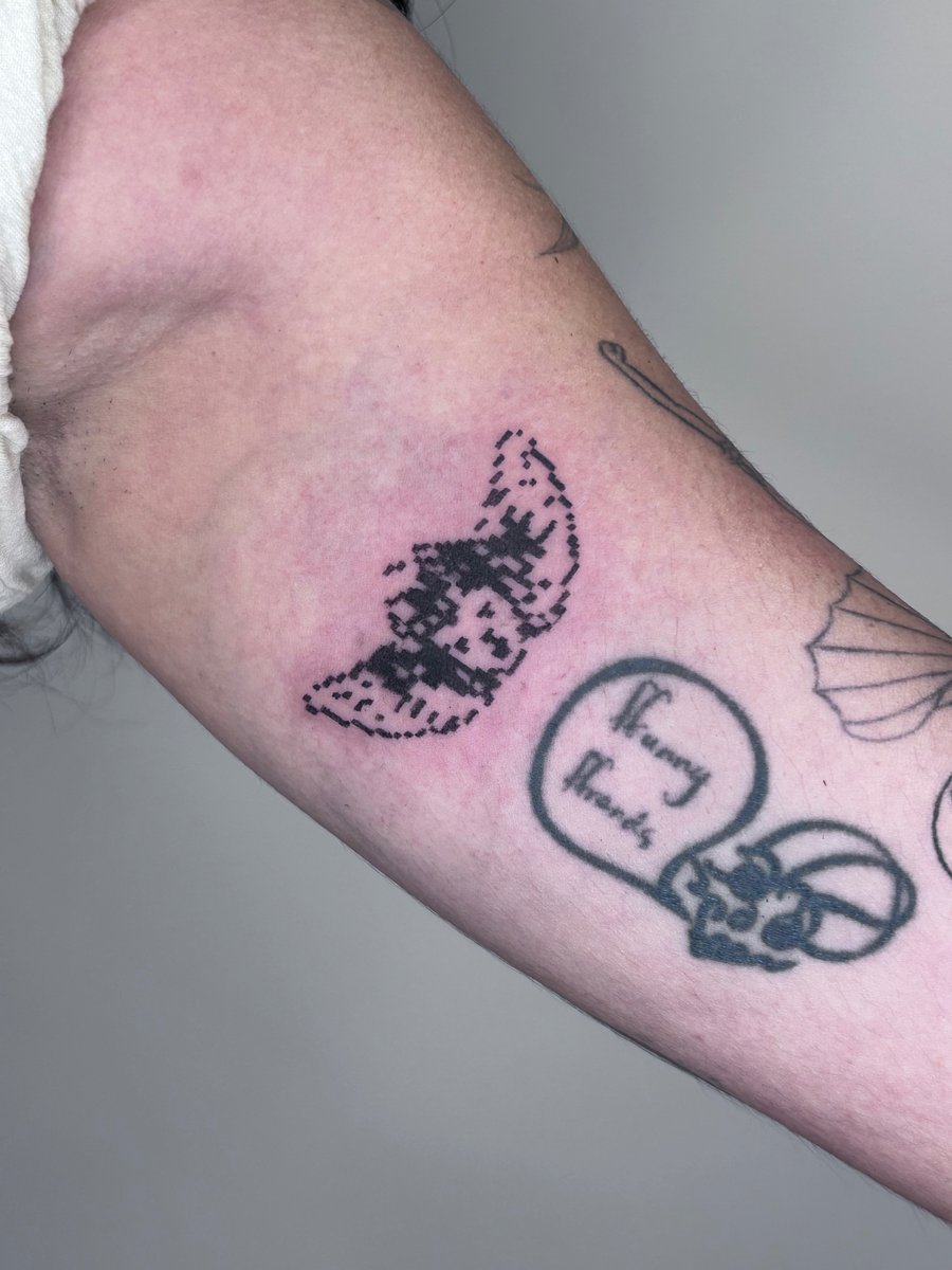 A minimalist pixelated butterfly tattoo in black ink on the inner arm, featuring an ignorant style design — by Brian Kies, los angeles