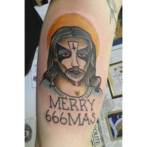 A traditional style tattoo of Jesus with 'Merry 666mas' text on the arm, featuring dark and graphic elements — by Samuel Connelly, san diego, ca