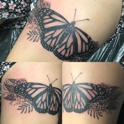 A black and grey butterfly tattoo with floral elements on the thigh, featuring delicate and ornate illustrative details — by Sandra Price, los angeles
