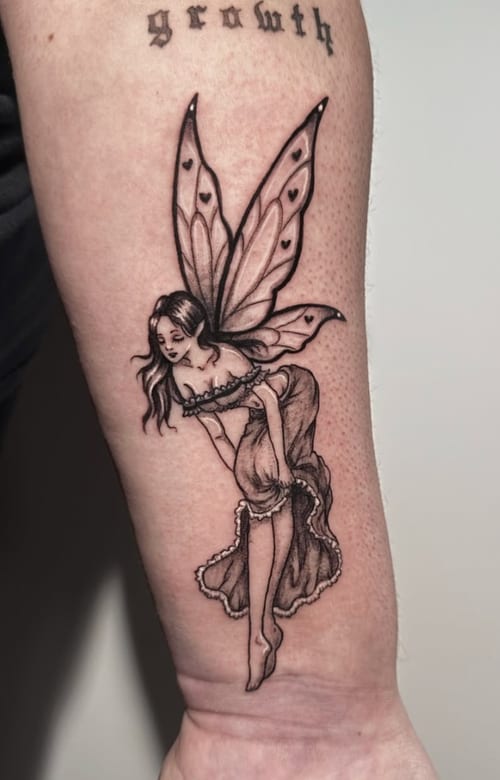 A black and grey fine line tattoo of a fairy on the forearm, featuring delicate wings and detailed linework — by Shelby Bianco, los angeles