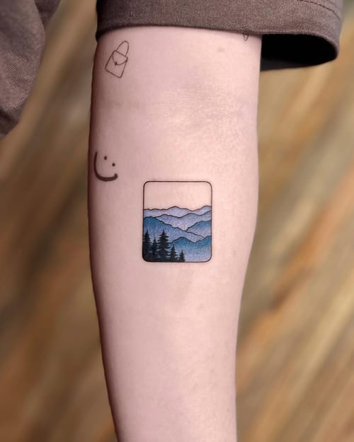 A minimalist mountain landscape tattoo on the forearm with a clean and colorful design — by Dylan Aiello, los angeles