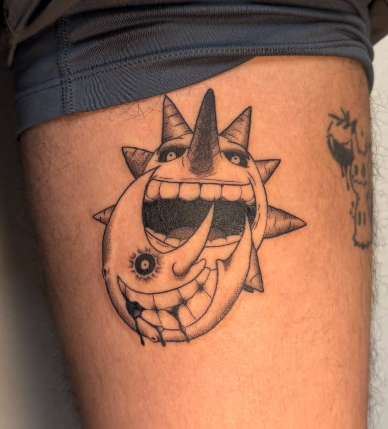 A black and grey illustrative tattoo on the thigh depicting a surreal sun and moon with exaggerated facial features and expressions — by NJ TATTOOZ, los angeles