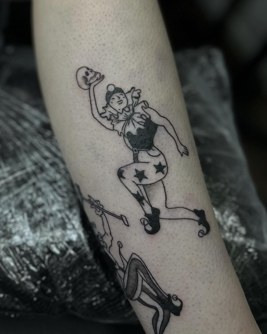 A blackwork tattoo of a jester holding a skull on the forearm — by Maddie Ramirez, los angeles
