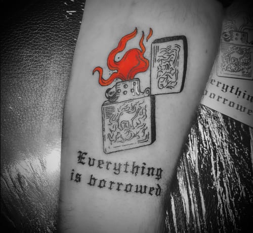 An illustrative tattoo on the forearm featuring an open lighter with red flames and the quote 'Everything is borrowed' in black ink — by Tag Devilish, los angeles