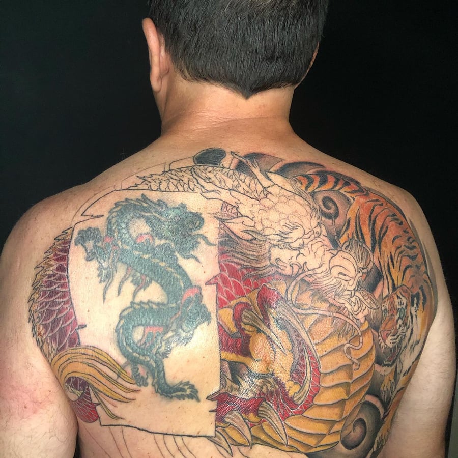 A colorful Japanese-style tattoo featuring a dragon and tiger on the back, showcasing bold and intricate designs — by Sandra Price, los angeles