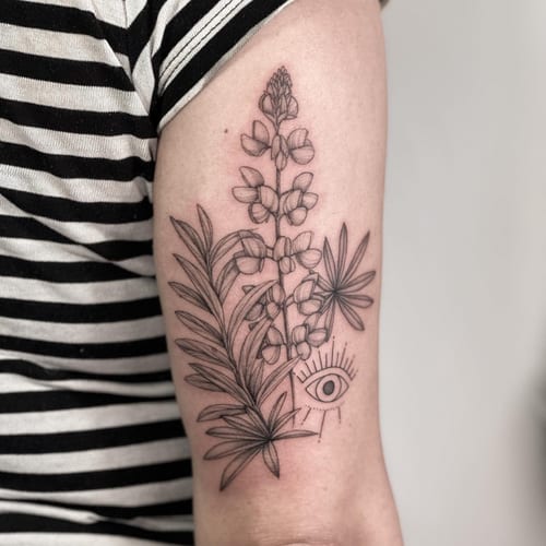 A delicate black and grey fine line tattoo of flowers and an eye on the upper arm — by Melanie Benoit, los angeles