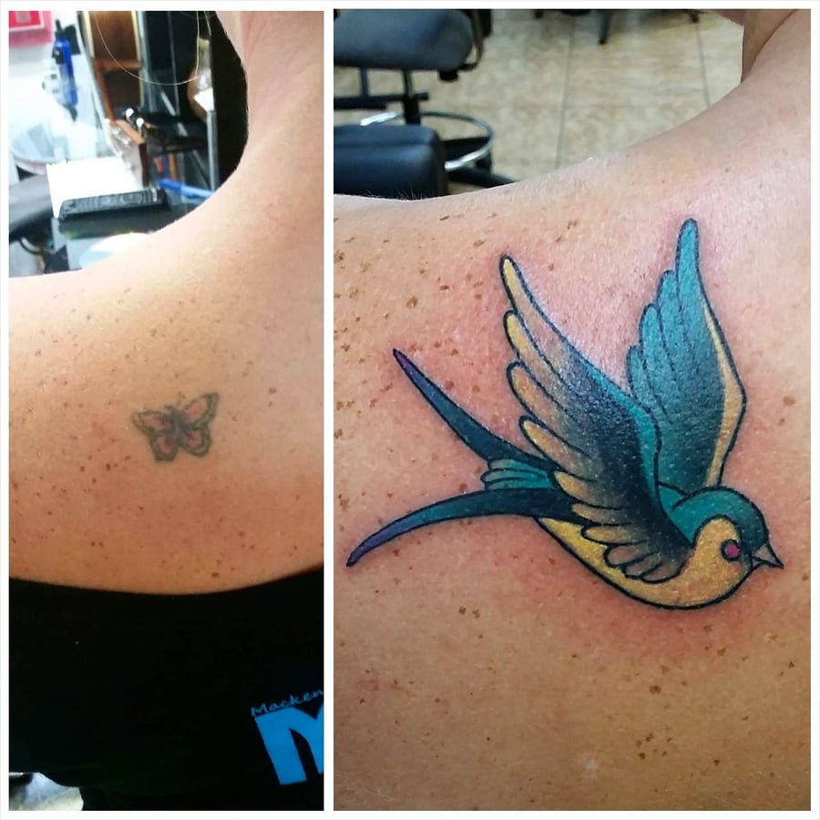A colorful traditional tattoo of a bird on the back, featuring bold outlines and vibrant shades of blue and yellow — by Dretty, los angeles