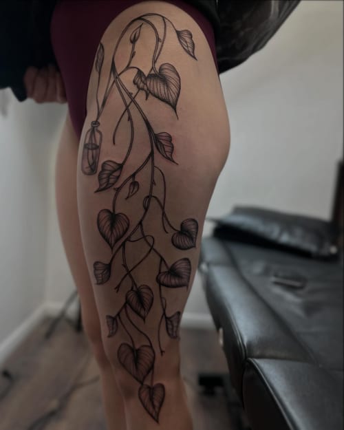 A delicate blackwork tattoo of a vine with heart-shaped leaves on the thigh — by Maddie Ramirez, los angeles