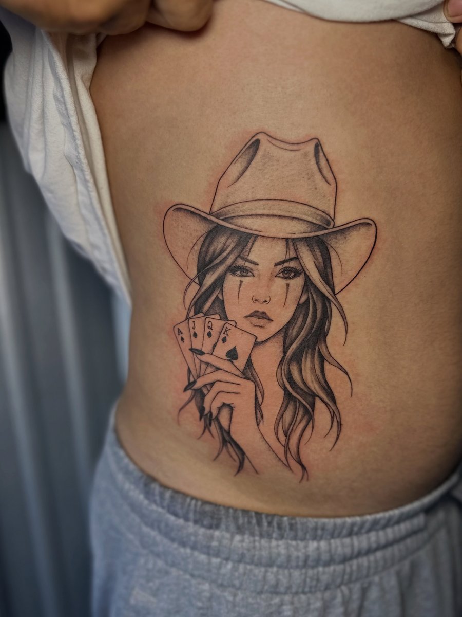 A bold blackwork tattoo of a woman holding playing cards on the side — by Maddie Ramirez, los angeles