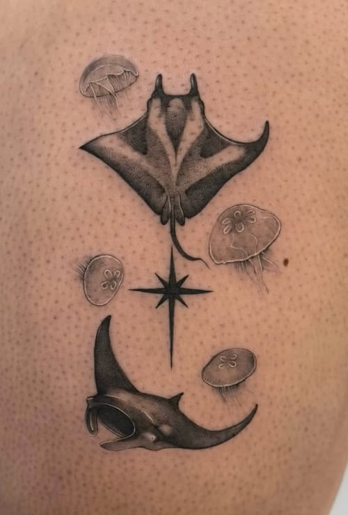 A black and grey tattoo on the back featuring realistic manta rays and jellyfish surrounding a compass rose — by otaybeatdown, los angeles