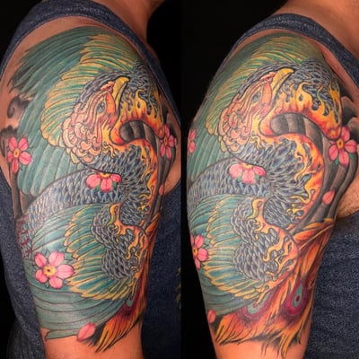 A colorful Japanese-style phoenix tattoo on the upper arm, featuring bold colors and ornate details with flowers — by Sandra Price, los angeles