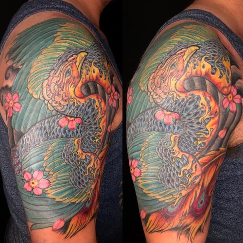 A colorful Japanese-style phoenix tattoo on the upper arm, featuring bold colors and ornate details with flowers — by Sandra Price, los angeles