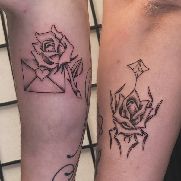 A minimalist blackwork tattoo featuring a rose with an envelope on the forearm, using clean linework and graphic style — by Miguel ANGELO, temecula, ca