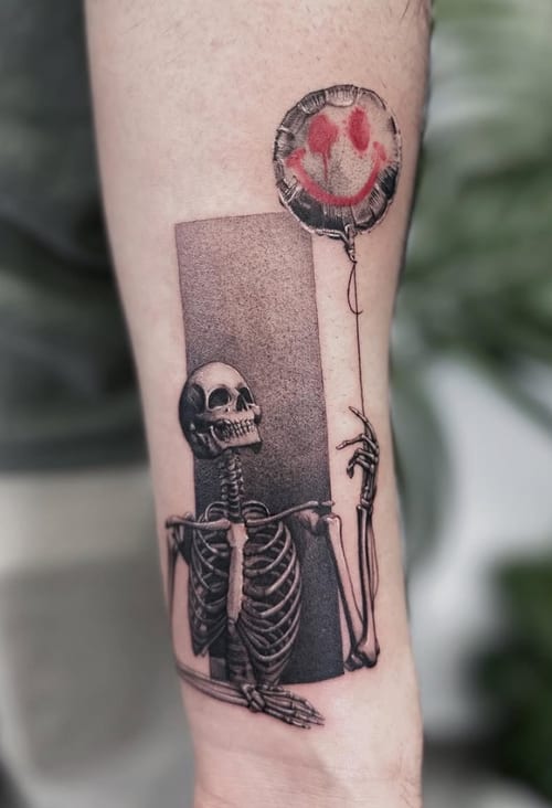 A surreal blackwork tattoo of a skeleton holding a balloon with a smiley face on the forearm, featuring a mix of black and red ink — by Jian Liang, los angeles
