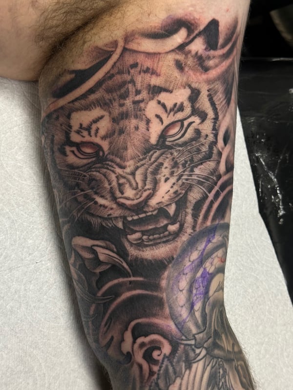 A bold black and grey tiger tattoo on the leg, featuring a graphic Japanese style with intricate details — by Humilde tattoos, los angeles