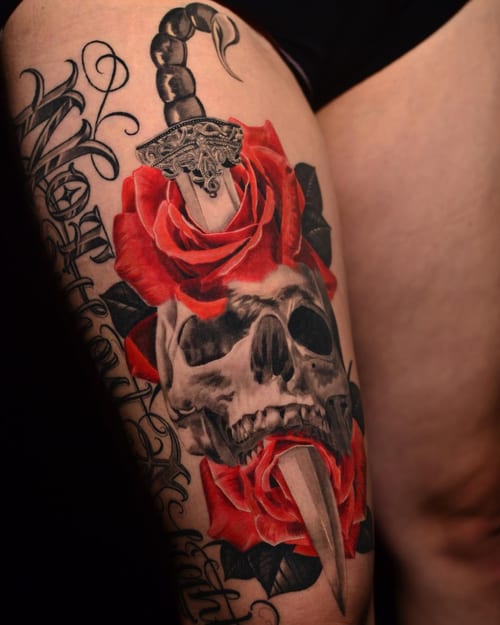 A bold neo-traditional tattoo of a skull with a dagger and red roses on the thigh, featuring a mix of realism and graphic elements — by Johnny Ayala, los angeles
