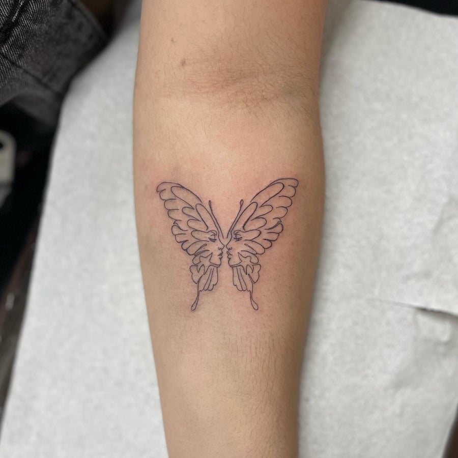 A minimal linework tattoo of a butterfly with faces on the forearm, featuring a delicate and simple design — by Sandra Price, los angeles