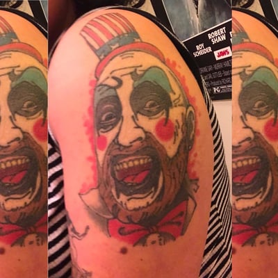 A colorful neo-traditional clown portrait tattoo on the upper arm with bold outlines and vibrant colors — by Sandra Price, los angeles